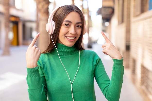 smiling cheerfully feeling happy and showing a concept listening music with headphones