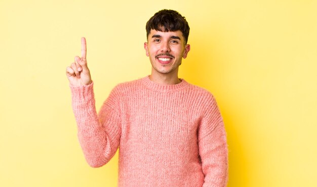 smiling cheerfully and happily pointing upwards with one hand to copy space