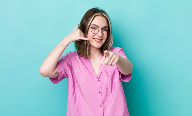 Smiling cheerfully and pointing to camera while making a call you later gesture talking on phone