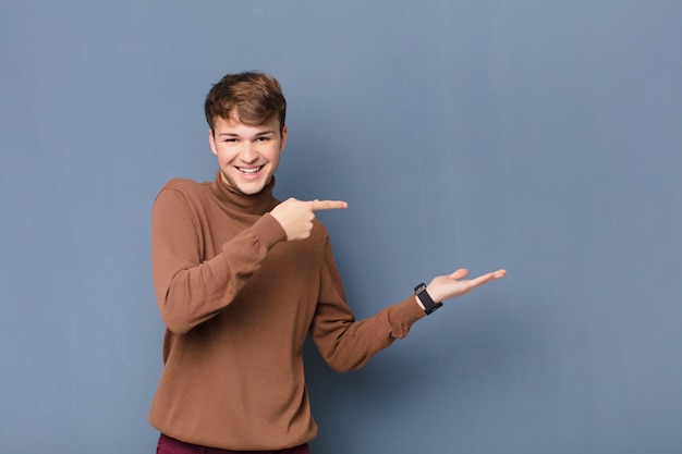 smiling cheerfully and pointing to copy space on palm on the side, showing or advertising an object