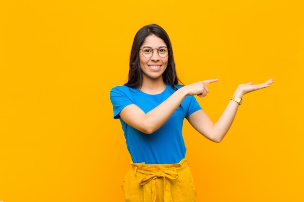 Smiling cheerfully and pointing on palm on the side, showing or advertising an object