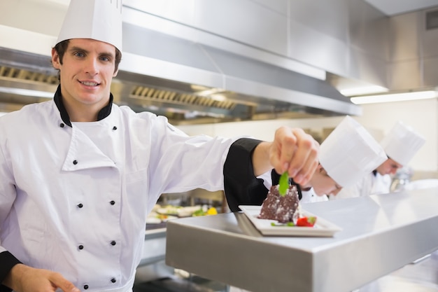 Chef sorridente che guarnisce la sua torta