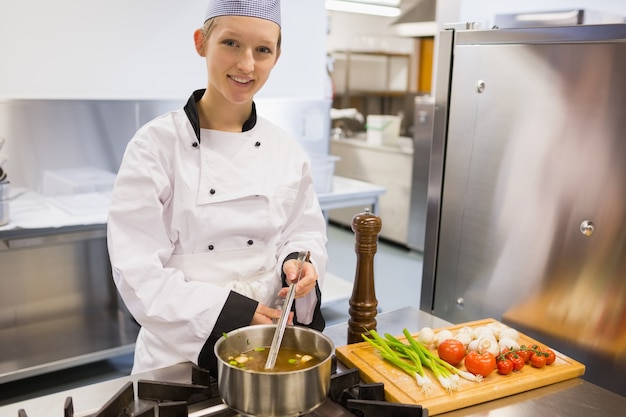 Smiling chef stirring soup 