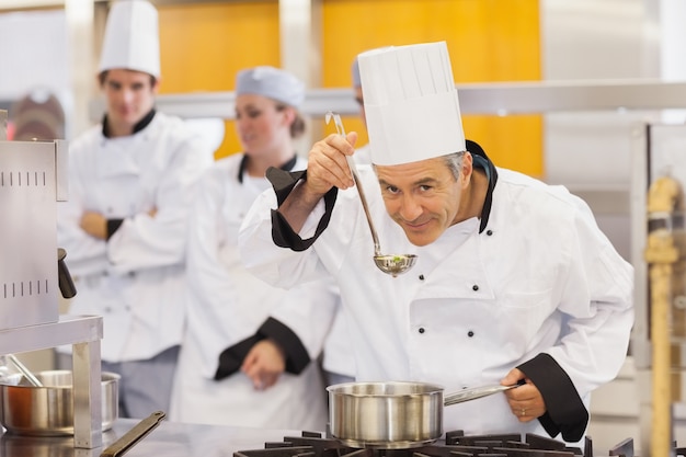 彼の学生の仕事を味わっている笑顔のシェフ