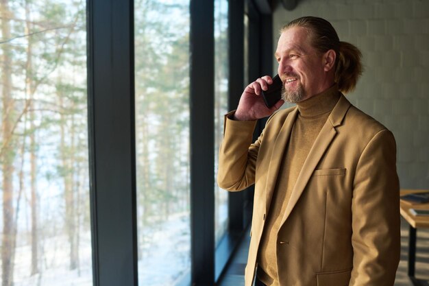 Smiling chief executive officer in formalwear looking through window