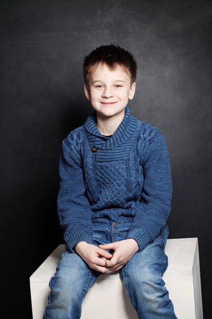 Smiling Child Boy in Blue Sweater on Dark Background