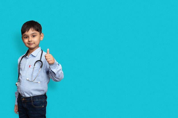 Фото Улыбающийся ребенок мальчик доктор в очках простой фон. док-мужчина в белой рубашке делает большие пальцы руки вверх. концепция медицины здоровья здравоохранения. копирование макета