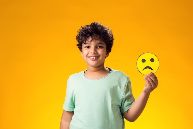 Photo smiling child boy holds emoticons with sad emotions