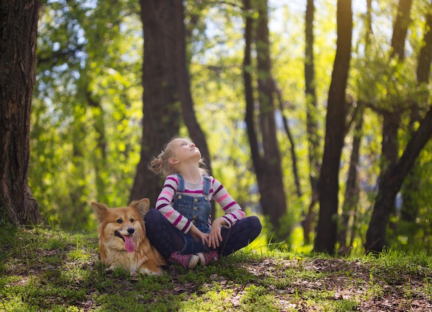 笑顔の子供の女の子と地面に座っている犬