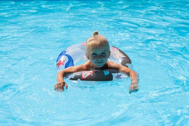 Smiling child girl swims with an inflatable ring in the pool