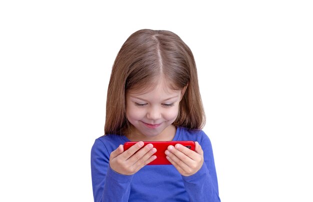 Smiling child looking at mobile phone watching cartoons isolated on white background waist up caucasian little girl of 5 years in blue