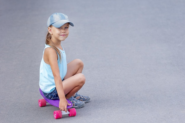 Smiling child sitting on skateboard on road