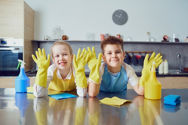 Smiling children do the cleaning in the kitchen