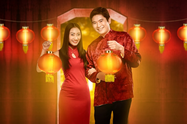 Smiling chinese couple with cheongsam dress holding red lanterns