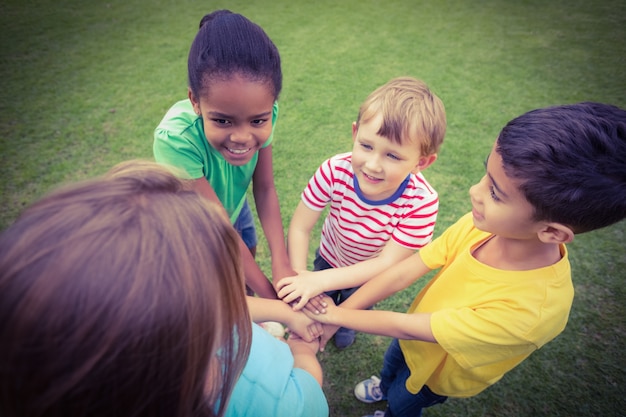 smiling classmates putting hands together