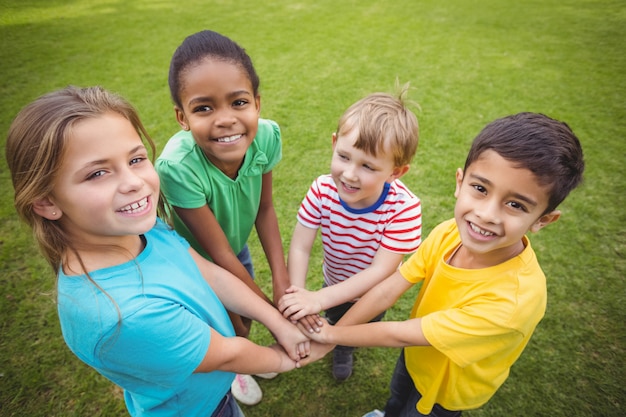 smiling classmates putting hands together