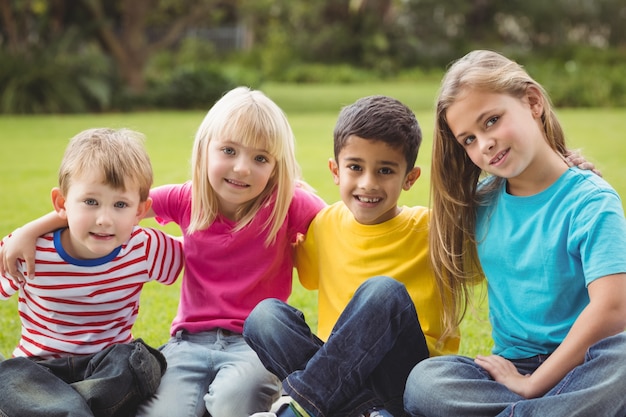 Smiling classmates sitting in grass 