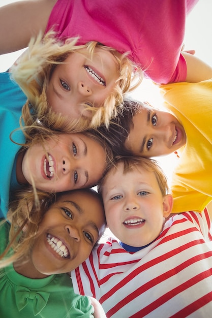 Smiling classmates with arms around looking down to camera