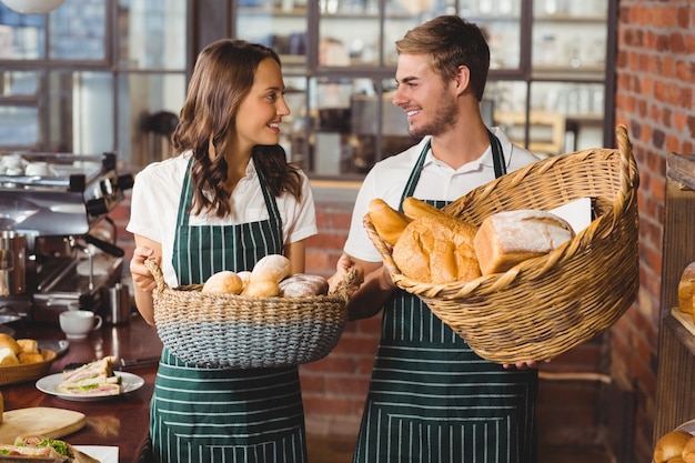 Улыбающиеся коллеги, держащие корзину хлеба