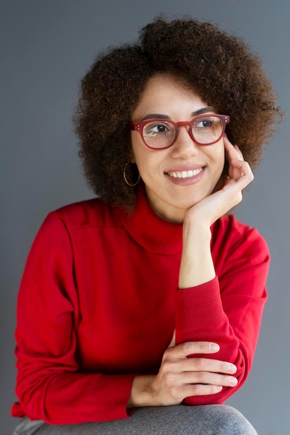 Smiling confident African American woman wearing red stylish eyeglasses sitting in office