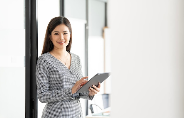 Photo smiling confident business leader looking at camera and standing in an office portrait of confident businesswoman using digital tablet during a meeting