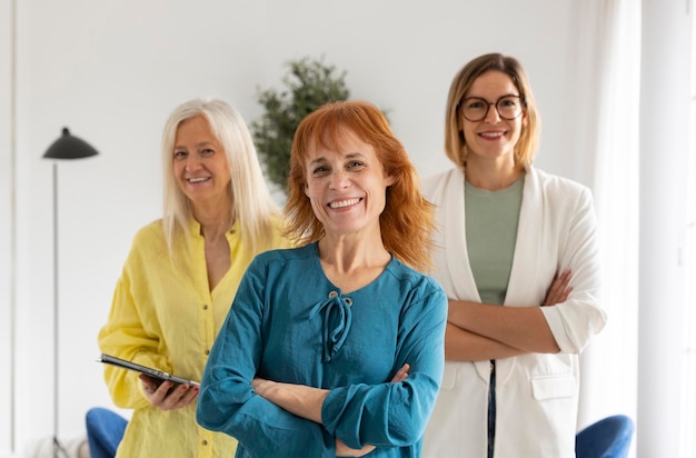 Smiling confident business leader looking at camera and standing in an office at three women team meeting confident with colleagues in board room