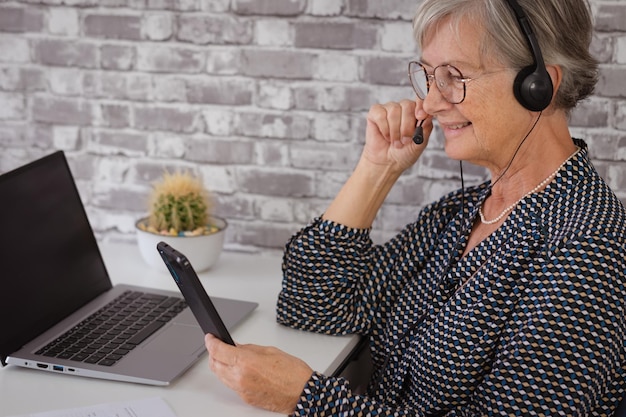 Smiling confident business woman wearing headphones talking in video call with smart phone