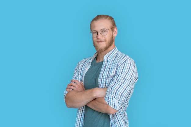 Smiling confident man arms crossed look at camera isolated on blue background