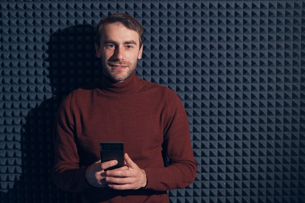 Smiling confident man holding smartphone over gray background