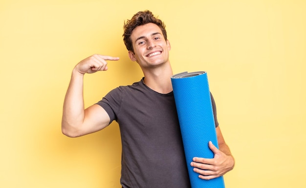 Smiling confidently pointing to own broad smile, positive, relaxed, satisfied attitude. yoga mat concept