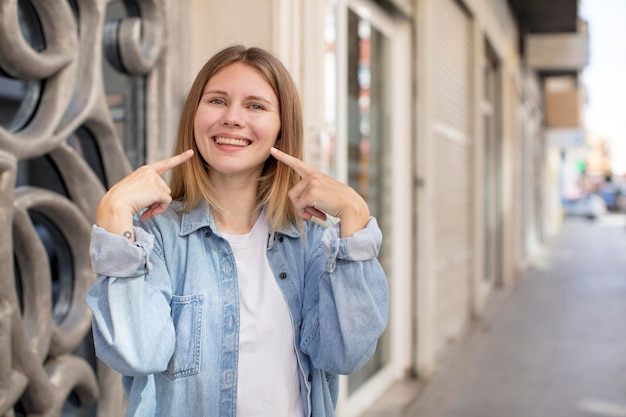 Photo smiling confidently pointing to own broad smile positive relaxed satisfied attitude