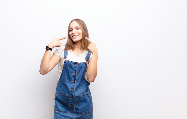 Sorridendo con fiducia indicando il proprio ampio sorriso, atteggiamento positivo, rilassato, soddisfatto