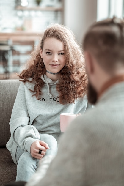 smiling to counselor. curly dark-haired teenage girl smiling to her private counselor while talking
