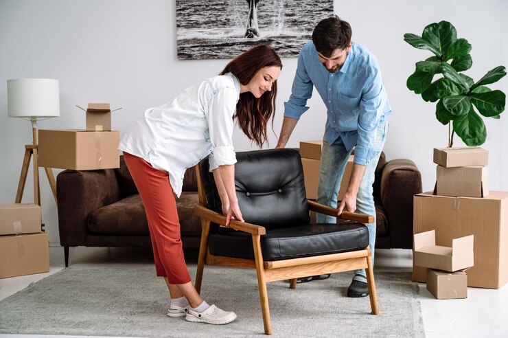 Smiling couple carrying modern chair together arranging furniture