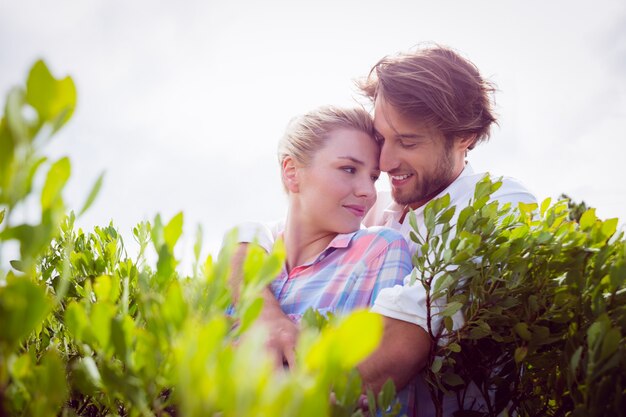 Smiling couple embracing outside among the bushes