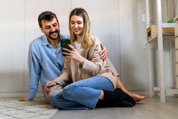 Smiling couple embracing while looking at smartphone People sharing social media on cellphone