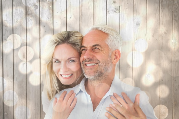 Photo smiling couple embracing with woman looking at camera against light circles on bright background