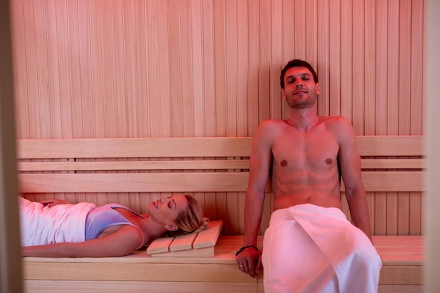 Smiling couple enjoying with eyes closed in sauna at health\
spa