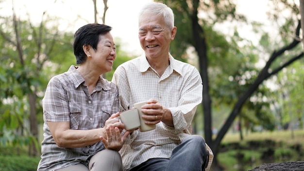 Photo smiling couple having drink while sitting in park