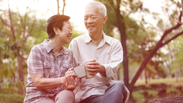 Smiling couple having drink while sitting in park