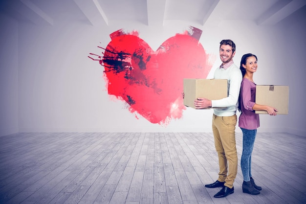 Smiling couple holding boxes against big room with white wall