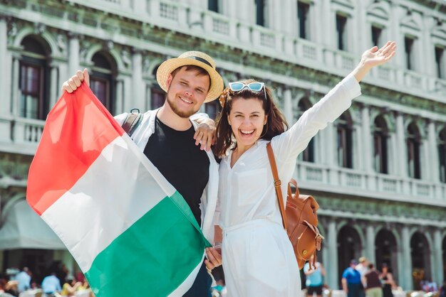 Photo smiling couple holding italian flag venice central square san marco