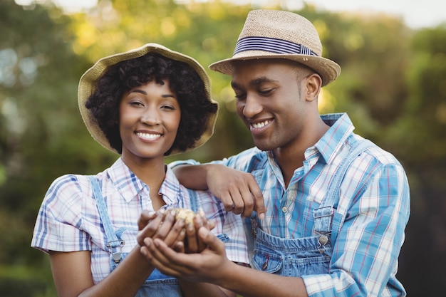 Smiling couple holding potatoes in the garden