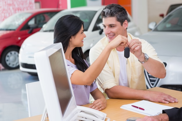 Foto coppie sorridenti che tengono la loro nuova chiave dell'automobile