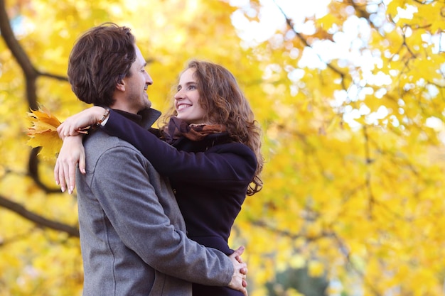 Smiling couple hugging in autumn park