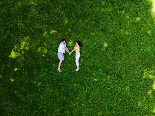 Smiling couple laying down on green grass copy space
