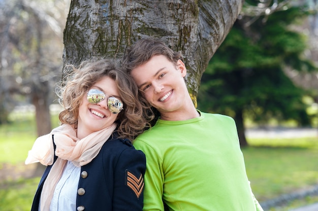 Smiling couple leaning on a tree