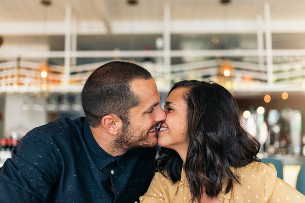 コーヒーショップでキスする恋人の笑顔のカップル。