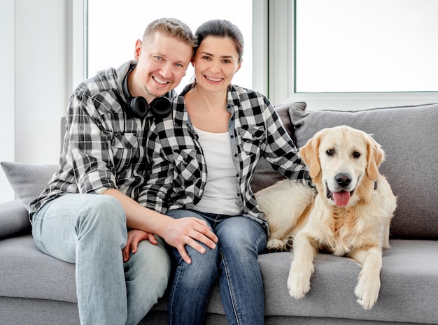 Smiling couple palming golden retriever