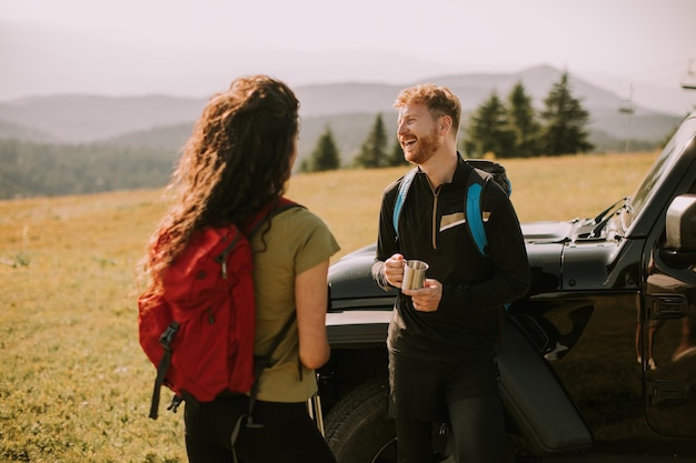 地形車両によるバックパックでハイキングの冒険を準備している笑顔のカップル